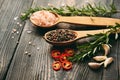 Close up photo of mixed peppercorns and sea salt in wooden spoons, fresh rosemary and garlic on dark wooden background Royalty Free Stock Photo