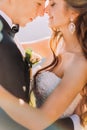 Close-up photo of newlywed young bride and groom with flower bouquet rubbing noses outdoors Royalty Free Stock Photo