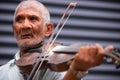 Close up photo of an old gray-hair man using violin playing a wonderful soulful melody outdoors turns his gaze to the