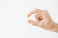 Close up photo of one round pill in young male hand. Man takes medicines with glass of water. Daily norm of vitamins, effective dr