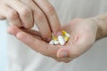 Close up photo of one round pill in young male hand. Man takes medicines with glass of water. Daily norm of vitamins, effective dr