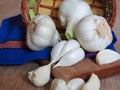Close up Photo of Organic Whole Garlic with some Unpeeled Cloves of garlic on oak tree wood background, basket and kitchen towels.
