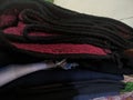 A close-up photo of a pile of clothing with someone holding a cell phone. This asset is suitable for fashion websites.