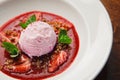 Close-up photo of pink ice cream scoop in plate with red jam, pieces of strawberries and mint leaves. Top view. Royalty Free Stock Photo