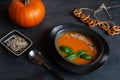 Close-up photo of plate with fresh homemade pumpkin cream soup with seeds and basil on dark background Royalty Free Stock Photo