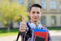 Close-up photo portrait of cheerful optimistic nice handsome cool self-assured guy holding copybooks in hands and making finger up