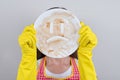 Close up photo portrait of depressed stressed wife closing covering hiding face behind crockery holding in hands isolated grey