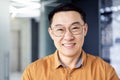 Close up photo portrait of successful young Asian investor, man in glasses smiling and looking at camera in shirt Royalty Free Stock Photo