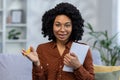 Close-up photo. Portrait of a young African American woman designer, freelancer looking at the camera smiling, holding a Royalty Free Stock Photo