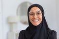 Close-up photo. Portrait of a young beautiful Muslim woman in a black hijab and glasses looking confidently and smiling Royalty Free Stock Photo