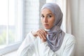 Close-up photo. Portrait of a young beautiful Muslim woman in a white hijab standing indoors by the window. He looks Royalty Free Stock Photo