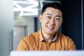 Close-up photo. Portrait of young handsome smiling Asian businessman in shirt in modern office Royalty Free Stock Photo