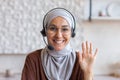 Close-up photo. Portrait of a young Muslim student woman in a hijab, glasses and a headset. He sits and smiles at the Royalty Free Stock Photo