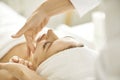 Close up photo of pretty relaxed young woman lying with closed eyes having facial massage in spa. Royalty Free Stock Photo