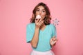 Close-up photo of pretty young girl with magic wand eating delicious cupcake, looking at camera