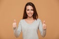 Close-up photo of pretty young woman in gray blouse showing thumb up gesture, looking at camera Royalty Free Stock Photo