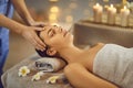 Close up photo of pretty young woman lying with closed eyes and having face or head massage in spa Royalty Free Stock Photo