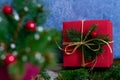 Close up photo of a red gift box in the background in focus. In the foreground, a fragment of coniferous branches in a vase Royalty Free Stock Photo