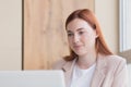 Close-up photo of a red haired business woman smiling while sitting at a computer, got a satisfactory result