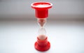 Close-up photo of red hourglass over white background.