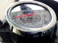 Close-up photo of a round motorbike speedometer with a chrome frame