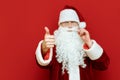 Close-up photo of Santa Claus`s hand shows thumb up, man looks into camera and smiles, focus on hand with liking gesture. Isolate Royalty Free Stock Photo