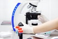 Close-up photo of scientist hands with microscope, examining samples and liquid