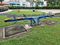 Close up photo of seasaw children playground with green surrounding it