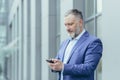 Close-up photo. Senior gray-haired man, a businessman calls a taxi from the phone,waits Royalty Free Stock Photo