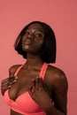 Close up photo of a sensual afro american girl in pink bra looking at the camera isolated over pink background Royalty Free Stock Photo