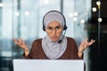 Close-up photo. Serious and strict and demanding Muslim female teacher in hijab and headset explaining and teaching