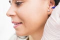 Close up photo of a side of the woman face, specialist female in gloves making dot with medical marker on a woman ear to Royalty Free Stock Photo