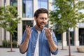 Close-up photo of a smiling young man standing on a city street talking on the phone through a loudspeaker, recording a Royalty Free Stock Photo