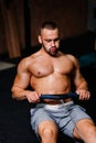 A muscular adult man doing exercises on a simulator on a gym background. Fitness, sports, and healthy lifestyle concept. Royalty Free Stock Photo