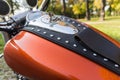 Close up photo of a tank of orange motorcycle with lots of chrome details, music speakers and riveted tie, made of genuine brown Royalty Free Stock Photo