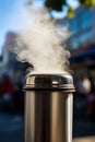 Close-up photo of a thermos mug of hot coffee, tea with steam on the evening street. Cold days, damp weather. Mood and concept of