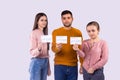 Close up photo of three friends standing in casual clothes in front of the camera holding the vaccine certifications of