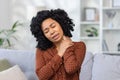 Close-up photo of a tired African-American woman sitting on the sofa at home, closing her eyes, holding on to something Royalty Free Stock Photo