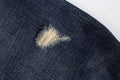 Close-up photo of torn blue jeans. Ripped denim blue cloth background Royalty Free Stock Photo