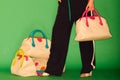 Close up photo of trendy violet bag with fur trinket in hands of fashionable woman posing in street with blooming spring Royalty Free Stock Photo