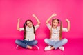 Close up photo two little age she her girls hands arms up best friends sit floor legs crossed winners wearing casual