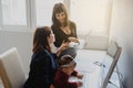 Photo of two women in office outfit working on computers and discussing a report on the floor; one of them is with a baby girl in Royalty Free Stock Photo