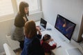 photo of two women in office outfit working on computers and discussing a report; one of them is with a baby girl in her arms