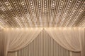 photo of a white ceiling and a part of a wall decorated with tulle and lights in a wedding banquet hall