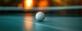 Close-up photo of white table tennis ball sitting on blue table tennis table. Net blurred in background. Selective focus Royalty Free Stock Photo