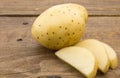 Close up photo of whole fresh potato and slices on wood table Royalty Free Stock Photo