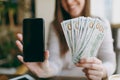 Close up photo of woman in coffee shop at table with bundle of dollars, cash money, mobile phone with blank empty screen