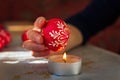 Close up photo of woman hand remove wax from easter egg with candle fire. Tradition method of painting