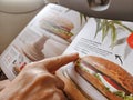 Woman passenger looking at the onboard menu and ordering a sandwich during a flight on the plane