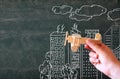 Close up photo of woman's hand holding wooden toy airplane against chalkboard with city illustration